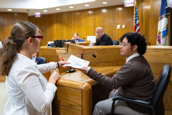 A Shenandoah student receives a document from a fellow student at the witness stand during a mock trial scrimmage.