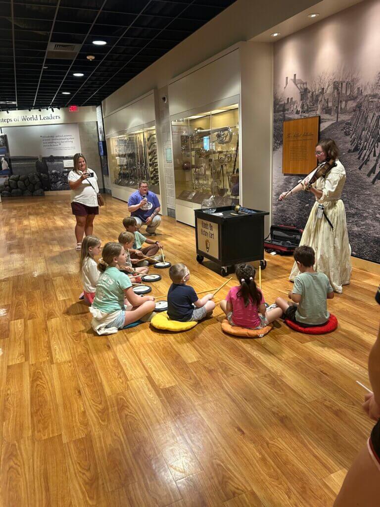 Music Education major and Civil War Era Studies certificate student Emily Mullen '26, performs on a stringed instrument for a group of young students. 