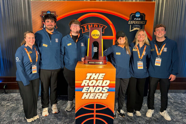 Six students pose with the NCAA Division I men's basketball championship tropy.