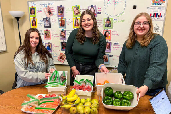 Students pose with fresh produce for Buzzy's Food Pantry.