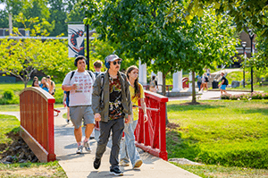 Students walking on campus on red bridge