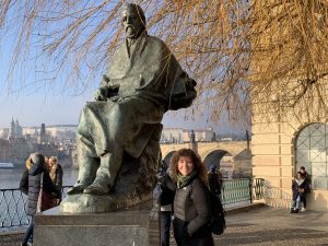 study abroad advisor standing next to Bedřich Smetana statue in front of Vltava River