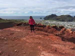 study abroad advisor standing on Eldfell volcano above homes in Heimaey and Atlantic Ocean