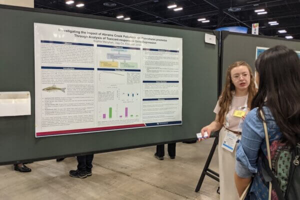 A student presents her research poster at a conference.