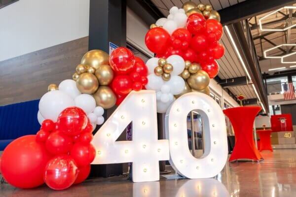 A balloon sculpture featuring red, gold and white balloons surrounds a lit "40" sign in the Hazel-Pruitt Armory at Shenandoah University to celebrate the 40th anniversary of the Children's Literature Conference.