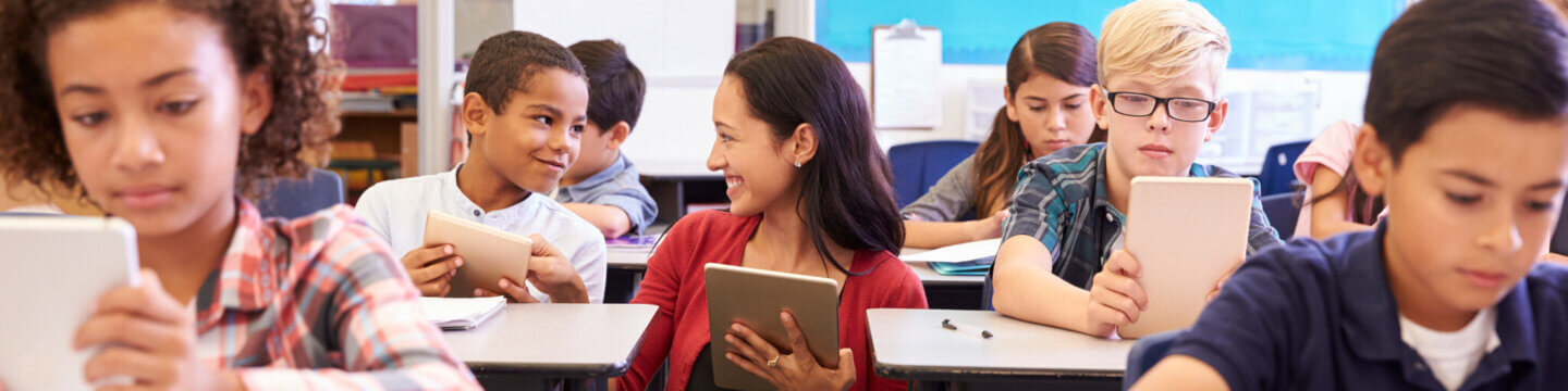 Classroom setting of 9-10 year old children; teacher assisting a student