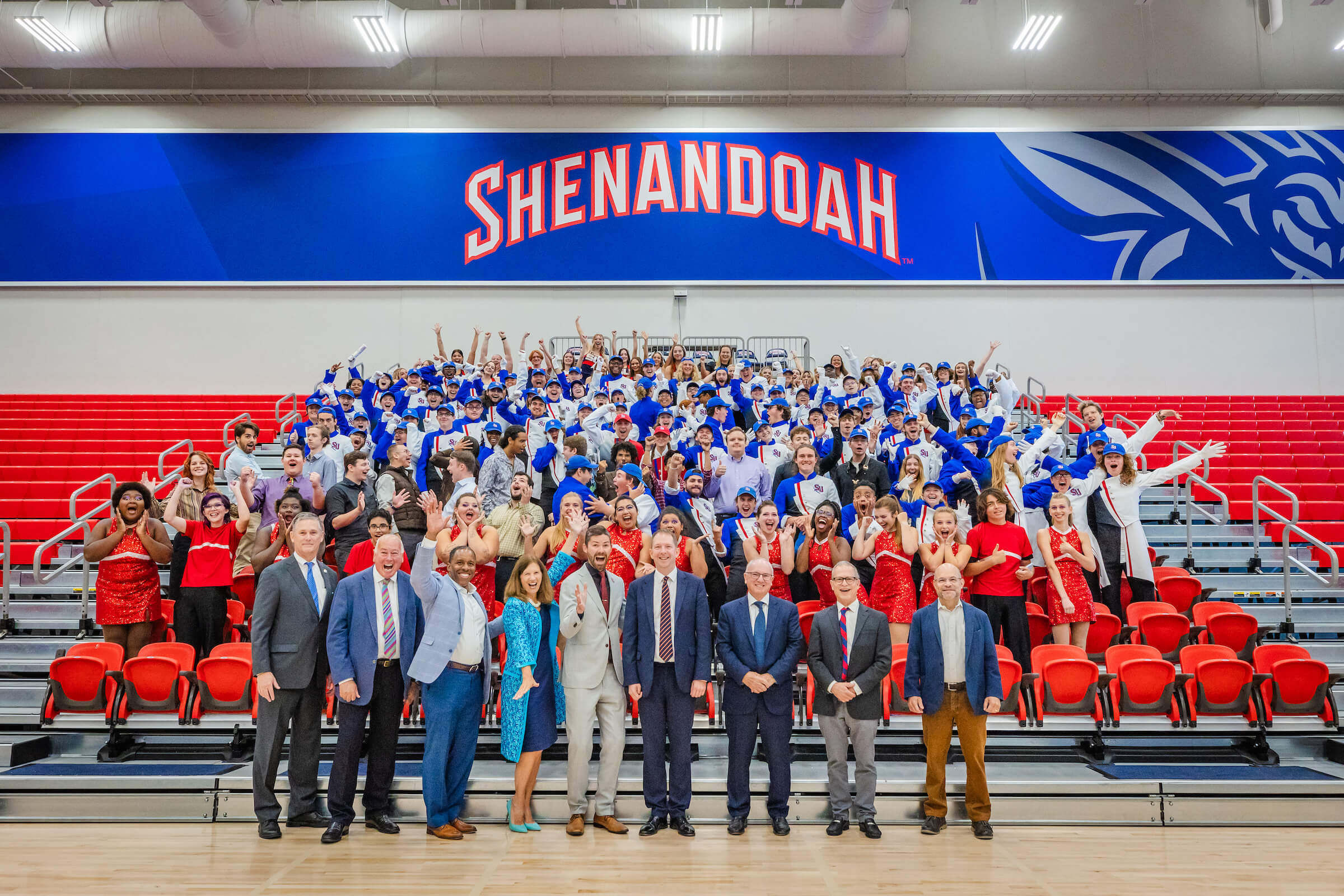 Shenandoah University Marching Band, cheerleaders, Studio Big Band, representatives from Shenandoah University, and organizers of London's New Year's Day Parade pose for a group photo in the Wilkins Athletics & Events Center