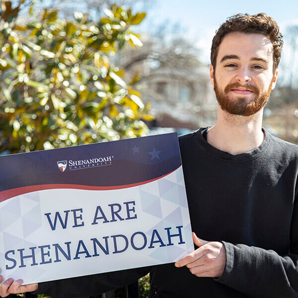 Student holding "WE ARE SHENANDOAH" sign