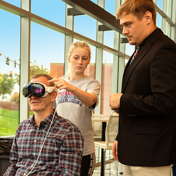 Students assist viewer with headset for "The Great Experiment" viewing