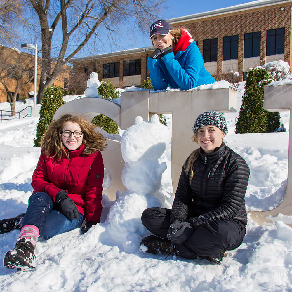 Students in snow at SU sign