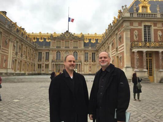 A photo of Donovan Stokes (left) and Thierry Barbé in front of Versailles