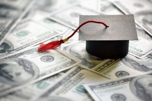 graduation cap onto of $100 bills