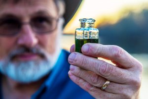 Shenandoah University Environmental Studies and Biology Professor Woodward Bousquet holds up a water sample.