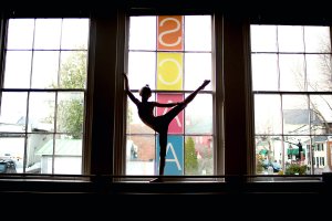 SCAA student doing a ballet pose in front of the SCAA sign.