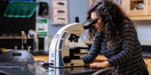 A Shenandoah University student looks through a microscope
