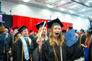 A Shenandoah University graduate celebrates with their diploma at the end of University Commencement 2023