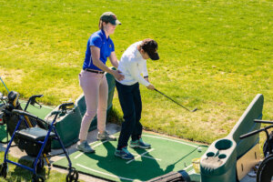 A Shenandoah University physical therapy student works with an adaptive athlete during the First Swing Seminar and Learn to Golf Clinic