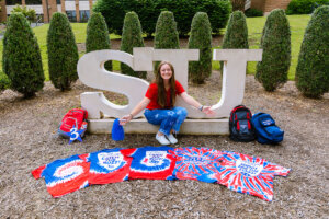 Victoria Hannen with the orientation T-shirts she's collected since 2019.