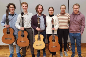 Colin Davin stands with guitar students