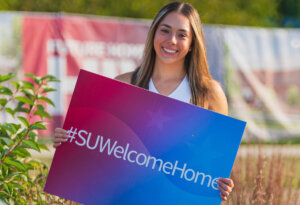 Move-In Day 2023 cheerleader holding SU Welcome Home sign.