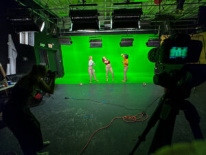 Dance students perform in front of a green screen with cameras set up in the foreground