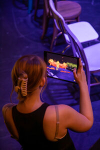 A Shenandoah University student uses an iPad for an augmented reality program that shows virtual dancers on-stage at Glaize Studio Theatre