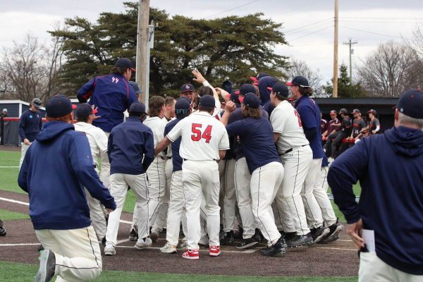 Shenandoah University players and coaches celebrate a walk-off grand slam at home plate.