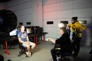 Shenandoah University esports student Dany Lobanov interviews another student in front of the garage bay doors of the Esports Arena.