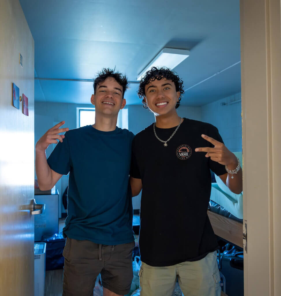 Two Shenandoah University students pose for a photo in the doorway of their residential hall.