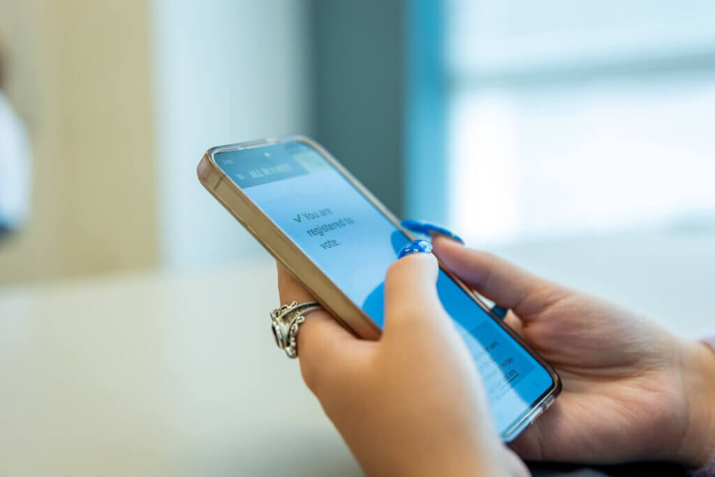 A student's phone screen reads, "You are registered to vote."