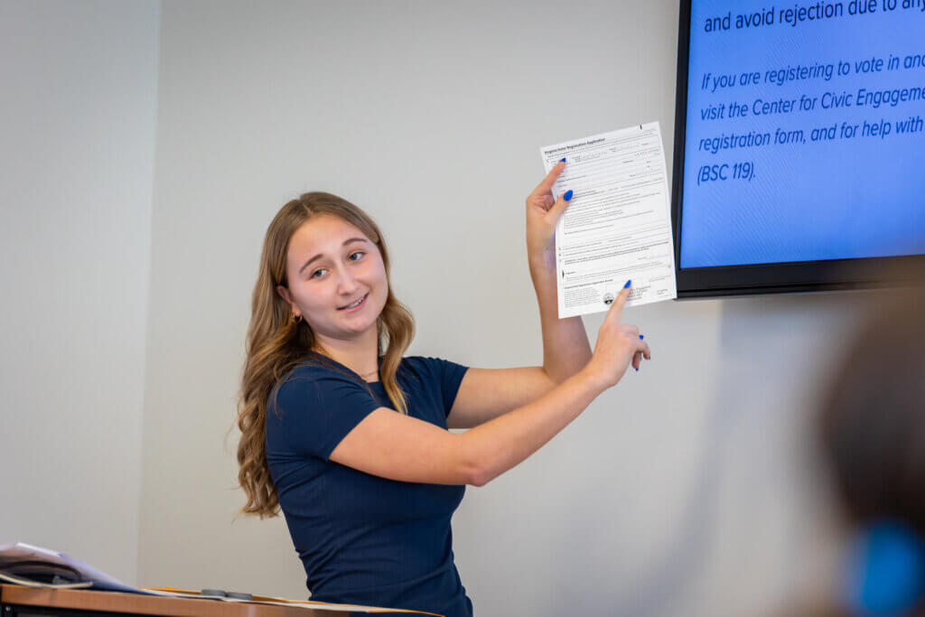 FYS Mentor Hailey Beaufort shows her class a voter registration form.