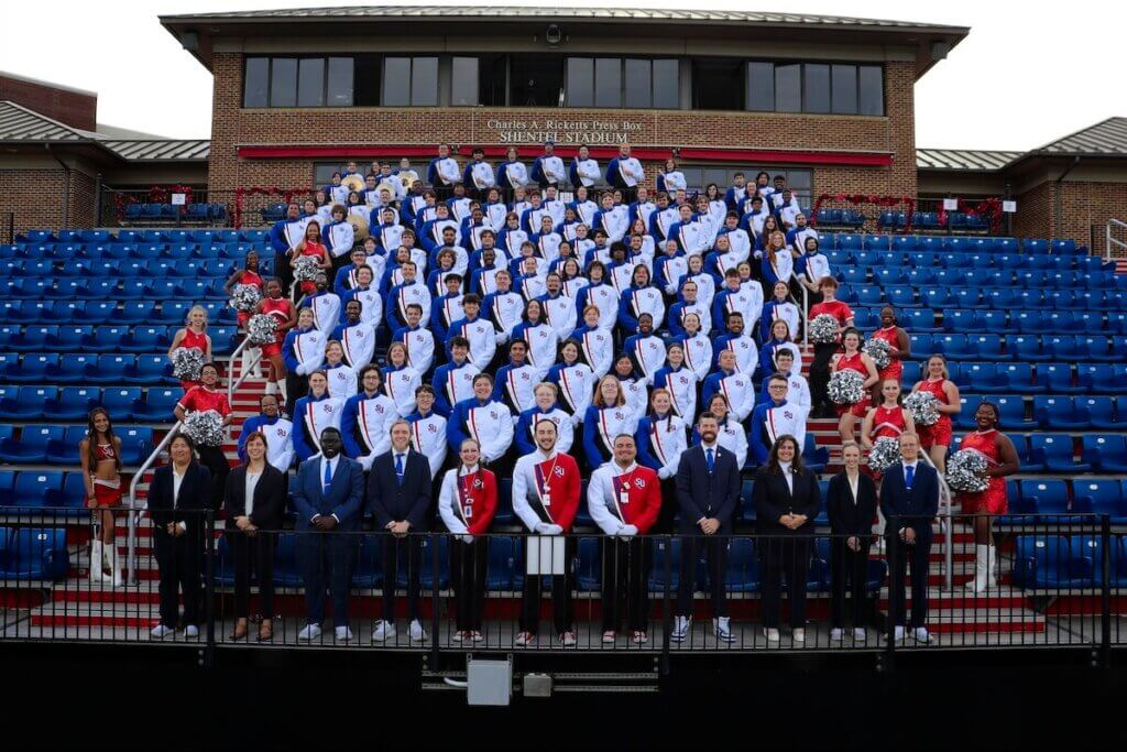 The full 2025-26 SU marching band poses for a photo in the stands at Shentel Stadium.