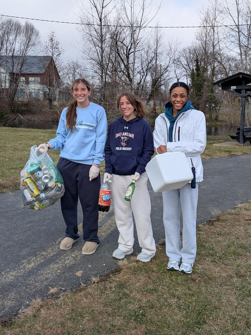 Shenandoah University students hold trash they collected along the Green Circle Trail next to Wilkins Lake.