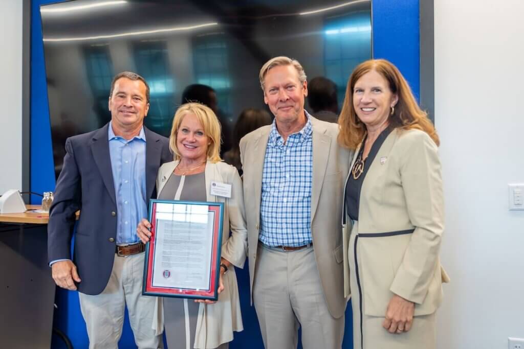 Kathleen Quarles holds a framed copy of a resolution of appreciation alongside Richie Wilkins, Billy Quarles and Tracy Fitzsimmons.