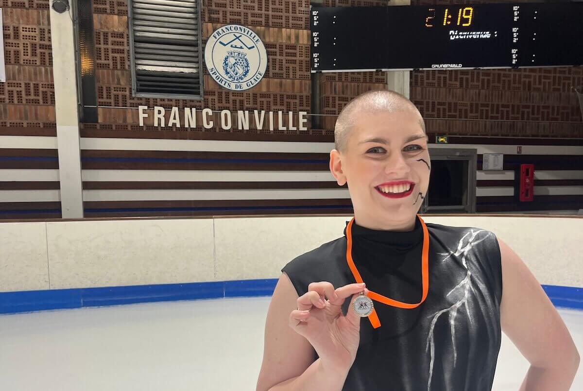 Shenandoah University nursing student and figure skater Evelyn Maletick '26, holding her small medal at a Theatre on Ice competition in France in 2026. She's wearing theatrical makeup and a black costume.