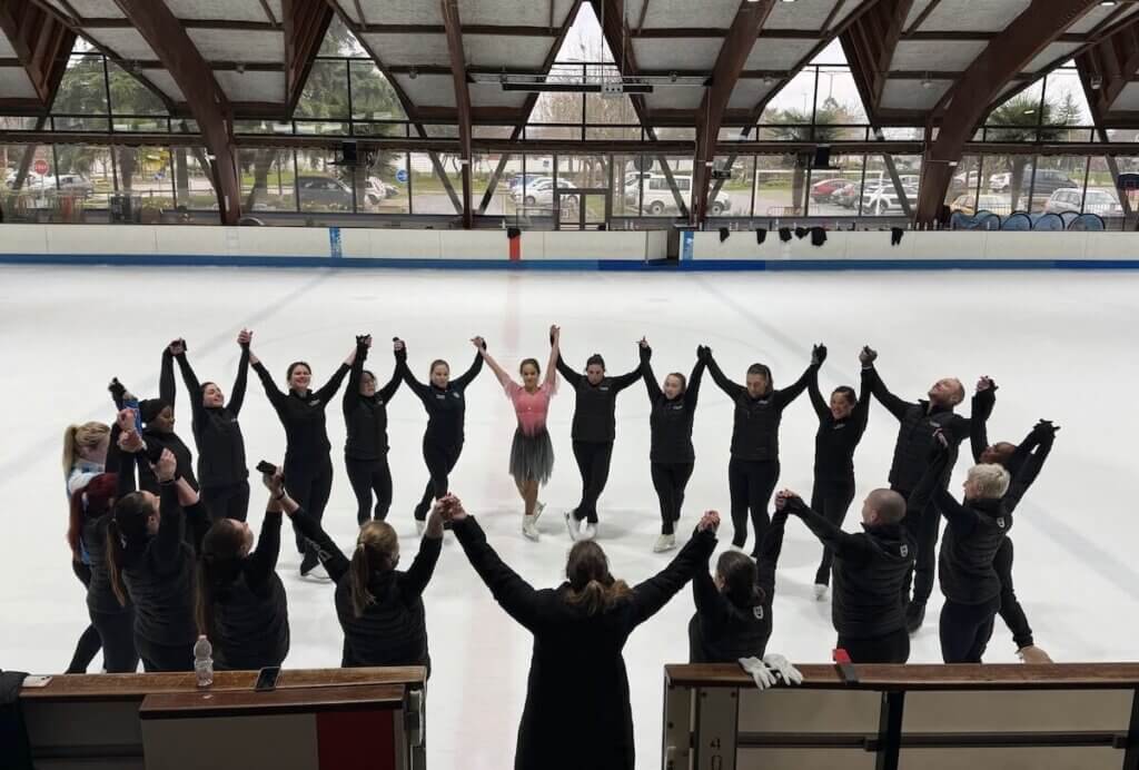 Capital Theatre on Ice in a circle, holding hands, at an ice arena in France. 