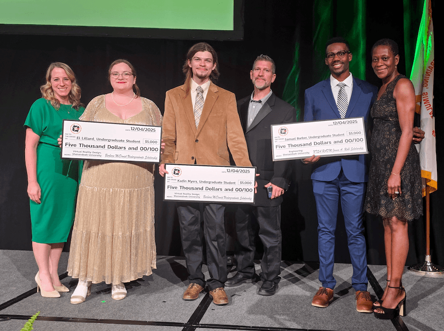 Students who won scholarships pose on stage with their parents while holding large checks.