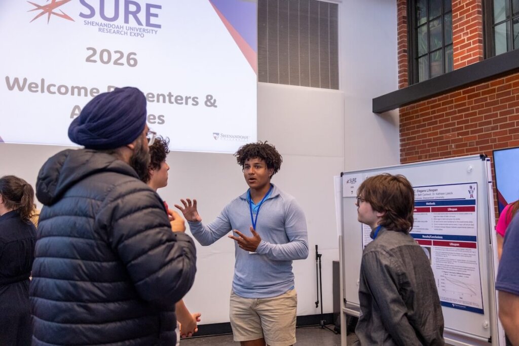 A student presents his research poster at the Shenandoah University Research Expo.