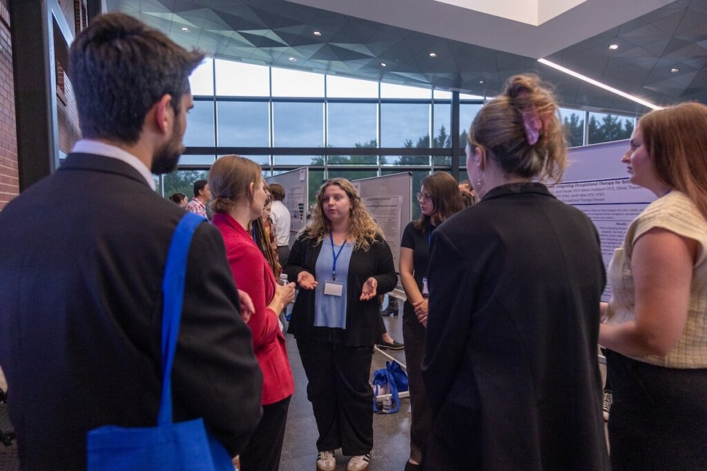 A student discusses her research poster at the Shenandoah University Research Expo.