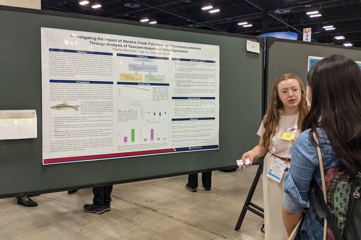A student presents her research poster at a conference.