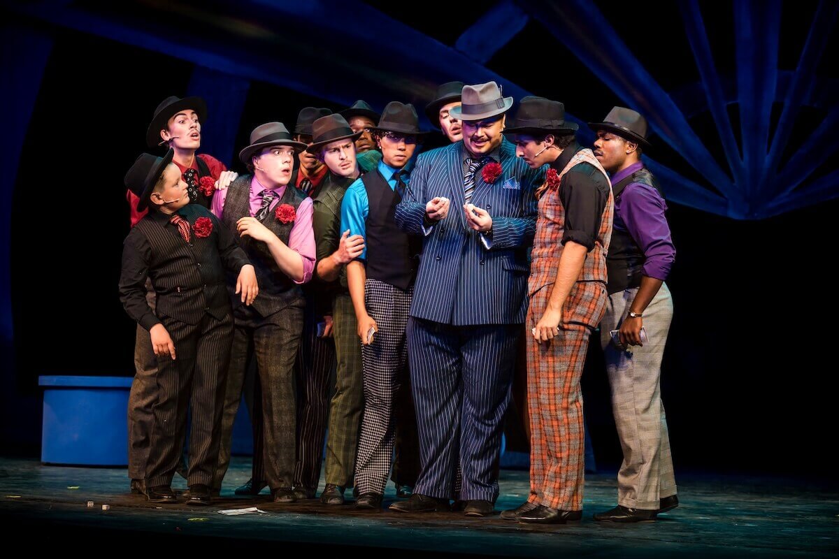 A group of individuals perform onstage during "Guys and Dolls."