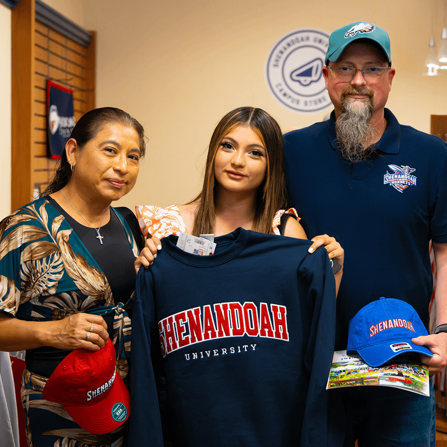 A student with two adults in the bookstore holding Shenandoah gear