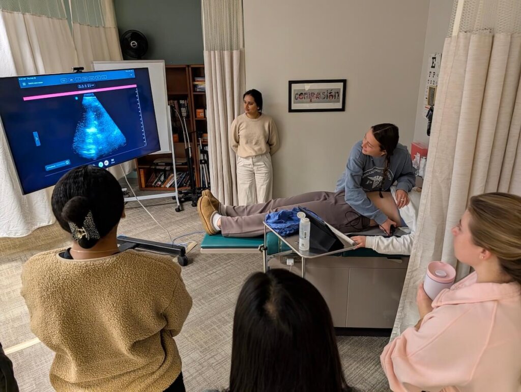 Students use a handheld ultrasound machine in an instructional environment.