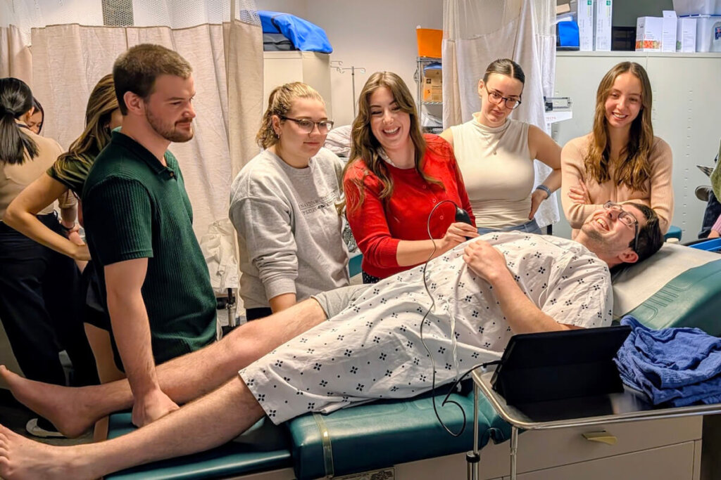 Students use a handheld ultrasound machine in an instructional environment.