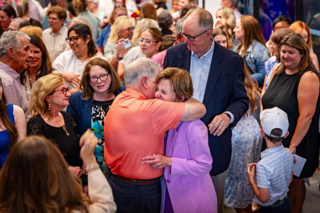Karen Huff shares a hug amidst a crowd of people.