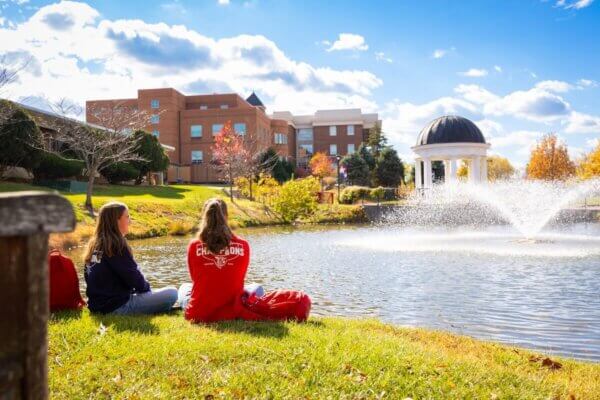 Two students sitting on the bank of the pond in Sarah's Glen.