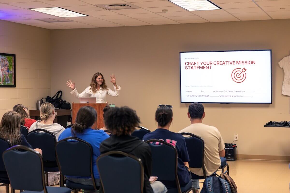 Enslow gestures while speaking from a podium to a group of Shenandoah students.