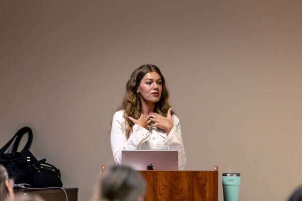 Singer-songwriter Enslow speaks at a podium.