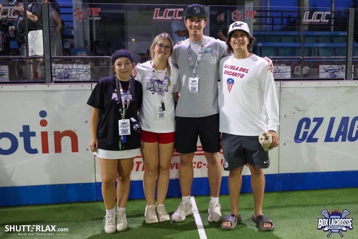 Shenandoah University exercise science major Katerina Deising '27 stands with three other young people - two young men and one other woman - at a European Box Lacrosse Championships venue in Prague, Czechia during the summer of 2026. Deising is blond, wearing classes, a white T-shirt and red shorts.