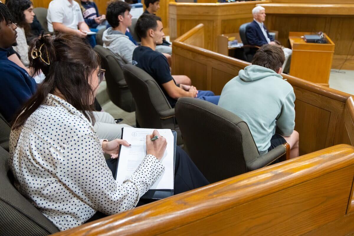 A Shenandoah student sits among the jury and takes notes during a mock trial scrimmage.